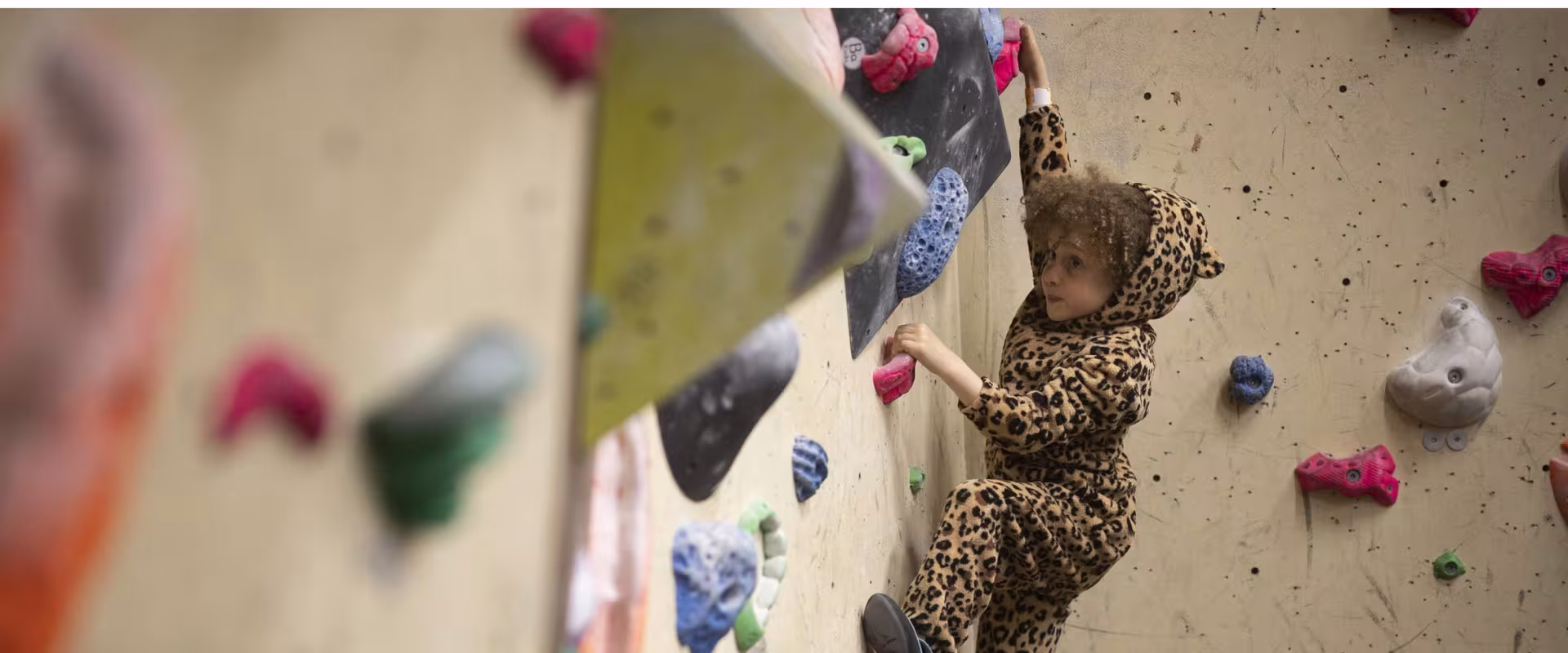 4 year old Kid bouldering wearing a leopard onesie 